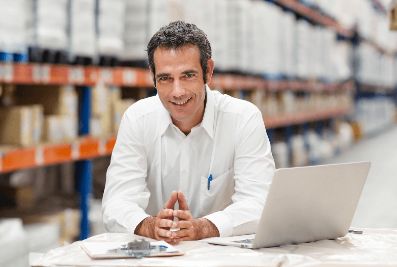 Image: A man siting in front of a laptop in a warehouse. Links to BJ's home page.