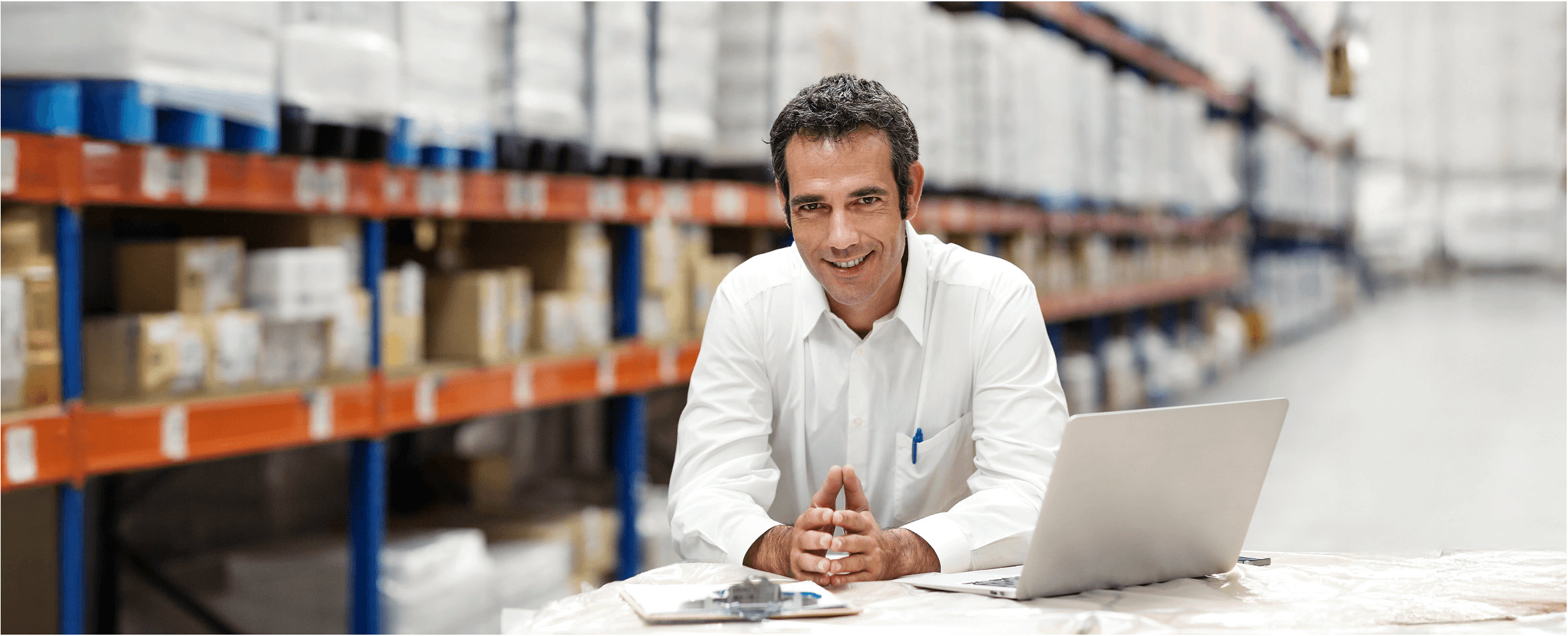 Image: A man siting in front of a laptop in a warehouse. Links to BJ's home page.