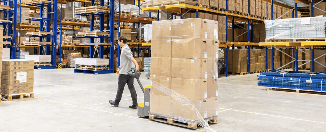 Image: A man pulling a palett of boxes in a warehouse. Links to BJ's home page.