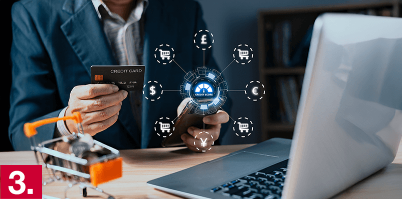 Image: A holding a credit card in front of a laptop.