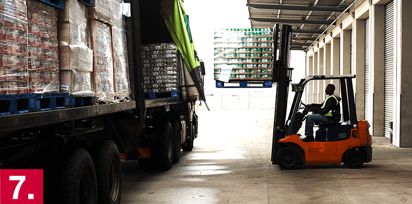 Image: A man driving a forklift toward a truck.